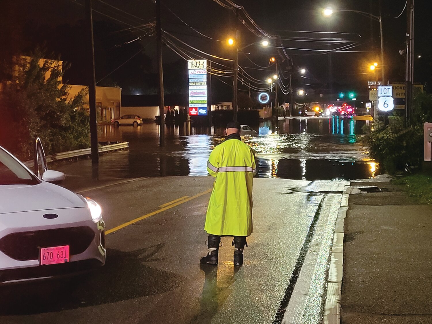 SOAKED SENTINEL: Later Monday night, the stranded vehicle continued to float around the roadway as the waters rose but eventually receded. Standing guard, Mike Edwards of the JPD BCI, kept motorists from driving through the water.
